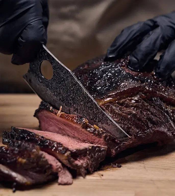 Matsato Osuren Chef Knife in action slicing meat on a cutting board